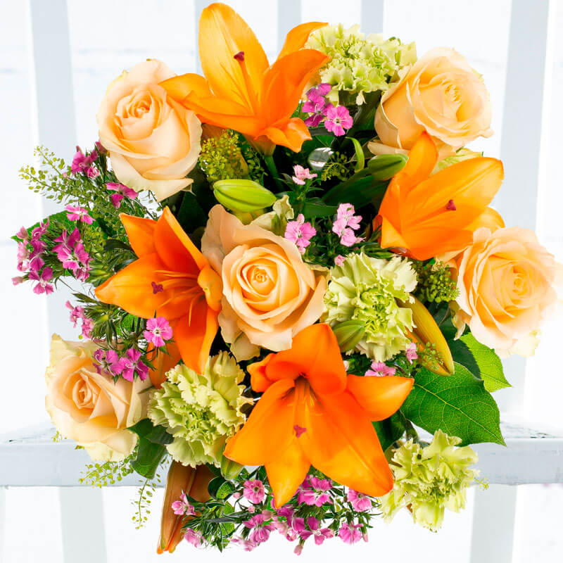 A bouquet of orange lilies, green carnations, pink sweet Williams, and peach roses.